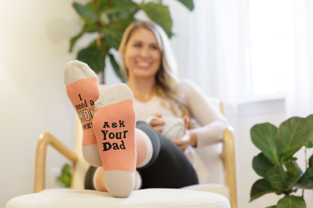 Person wearing socks with text, sitting on a chair with a blurred background